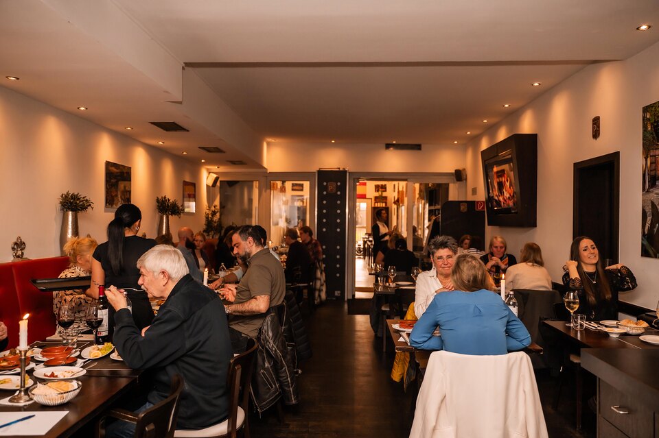 Gäste beim Abendessen im warm beleuchteten Restaurant Pelayo