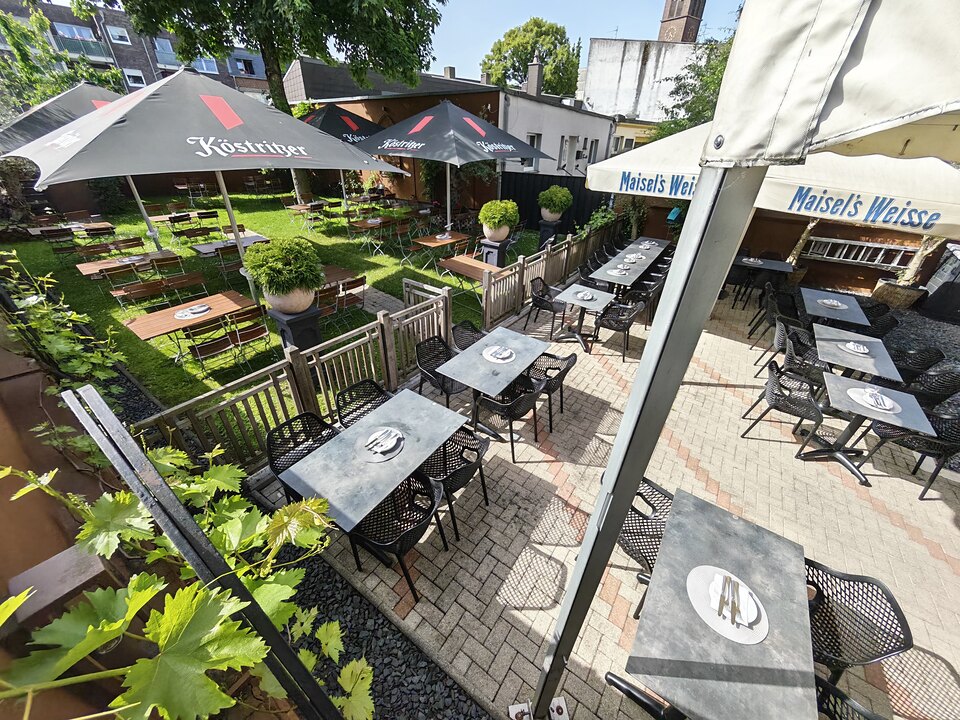 Blick über die Terrasse mit gedeckten Tischen und angrenzendem Garten